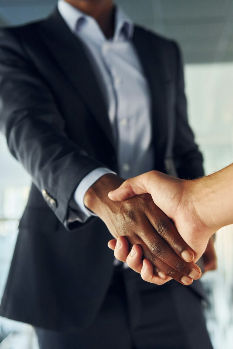 Doing handshake with customer. Young african american businessman in black suit is indoors